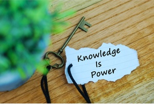 A wooden background with a key and torn paper with the phrase “Knowledge is Power” Domain Portfolio concept.