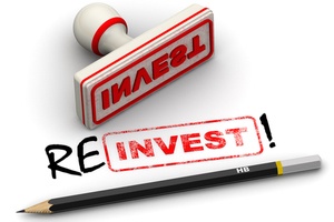 3d illustration of a red seal and the imprint of “Invest” corrected to “Reinvest” on white surface. Reinvest domain profits concept.